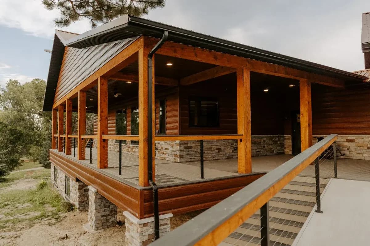 Custom log home exterior in Buffalo, Wyoming with covered porch, timber posts, and stone accents