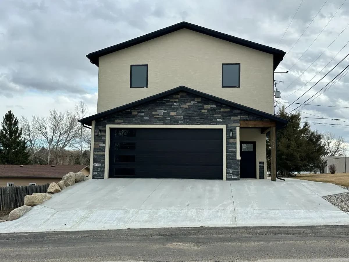 Modern custom home exterior with stone accents and black garage door in Buffalo, Wyoming